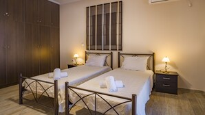 Ein Hotelzimmer mit zwei Betten, einem Kleiderschrank, einer Wand-Klimaanlage und Nachttischlampen.