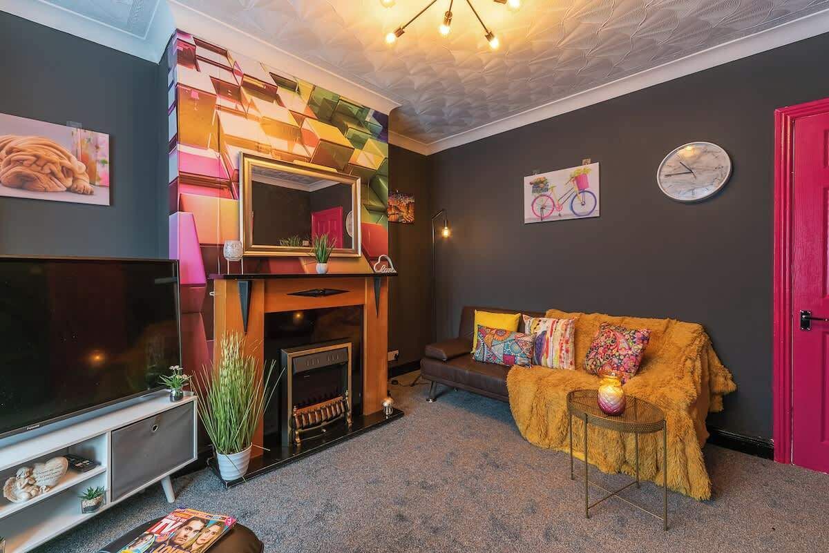 A living room with a fireplace, a sofa, a television, and a red door.