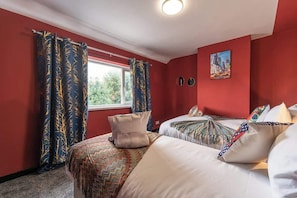 A room with two beds, red walls, and a window with curtains. - Spacious House, Garden, Private Parking, Near Hull Uni & Beverley (Kingston upon Hull)