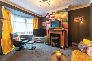 A modern living room with a fireplace, a flat-screen TV, and a comfortable seating area.
