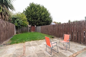 A backyard with a wooden fence, a grassy area, and two metal chairs. - Spacious House, Garden, Private Parking, Near Hull Uni & Beverley (Kingston upon Hull)