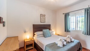 A neatly arranged hotel room with a bed, bedside tables, a wall clock, and a window with curtains. - Villa Maroma Viñuela by Ruralidays (Málaga)