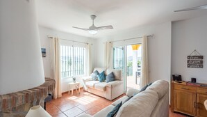 A spacious living room with a sofa set, a small table, and a wooden cabinet. - Villa Maroma Viñuela by Ruralidays (Málaga)