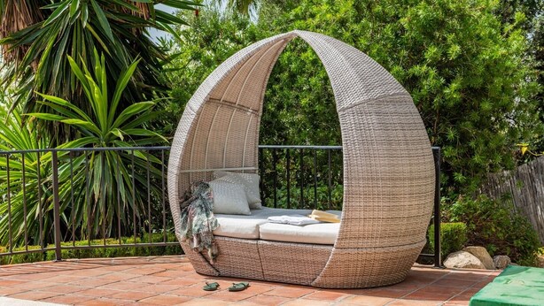 A wicker swing chair with a cushioned seat and backrest, placed on a brick patio surrounded by greenery. - Villa Maroma Viñuela by Ruralidays (Málaga)