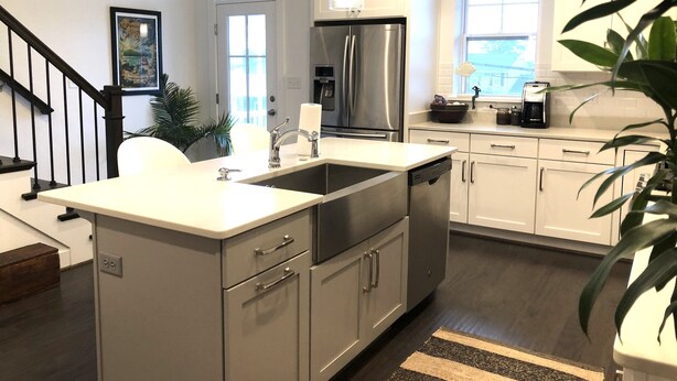 Una cocina moderna con refrigerador de acero inoxidable, armarios blancos y lavavajillas integrado.