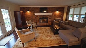 A living room with a fireplace, a sofa, a chair, and a coffee table. - Arrowstone Luxury Farmhouse in Historic Old Town, Niagara-on-the-Lake.  (Niagara-on-the-Lake)