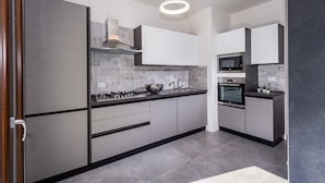 Cocina moderna con armarios grises, estufa a gas, microondas y un lavamanos.