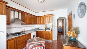 A kitchen with wooden cabinets, a microwave, and a stove. - Huerta La Niña Arenas Órgiva by Ruralidays (Granada)