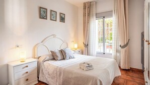 A neatly arranged bedroom with a bed, bedside tables, and a window with curtains. - Huerta La Niña Arenas Órgiva by Ruralidays (Granada)