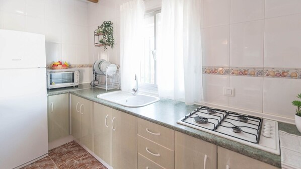 Une cuisine équipée d’un four à micro-ondes, d’un évier, d’une cuisinière et de placards.
