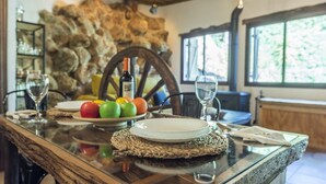 A dining table with plates, a bottle, and a fruit bowl. - Casa de La  Cascada Iznájar by Ruralidays (Córdoba)