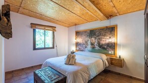 A bedroom with a bed, a window, a wall-mounted light, and a tapestry. - Casa de La  Cascada Iznájar by Ruralidays (Córdoba)