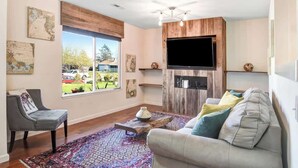 A living room with a sofa, a chair, a coffee table, a flat-screen TV, and a fireplace. - Sonoma Valley Vacation Home (Santa Rosa)