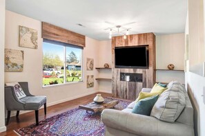 A living room with a sofa, a chair, a coffee table, a flat-screen TV, and a fireplace. - Sonoma Valley Vacation Home (Santa Rosa)