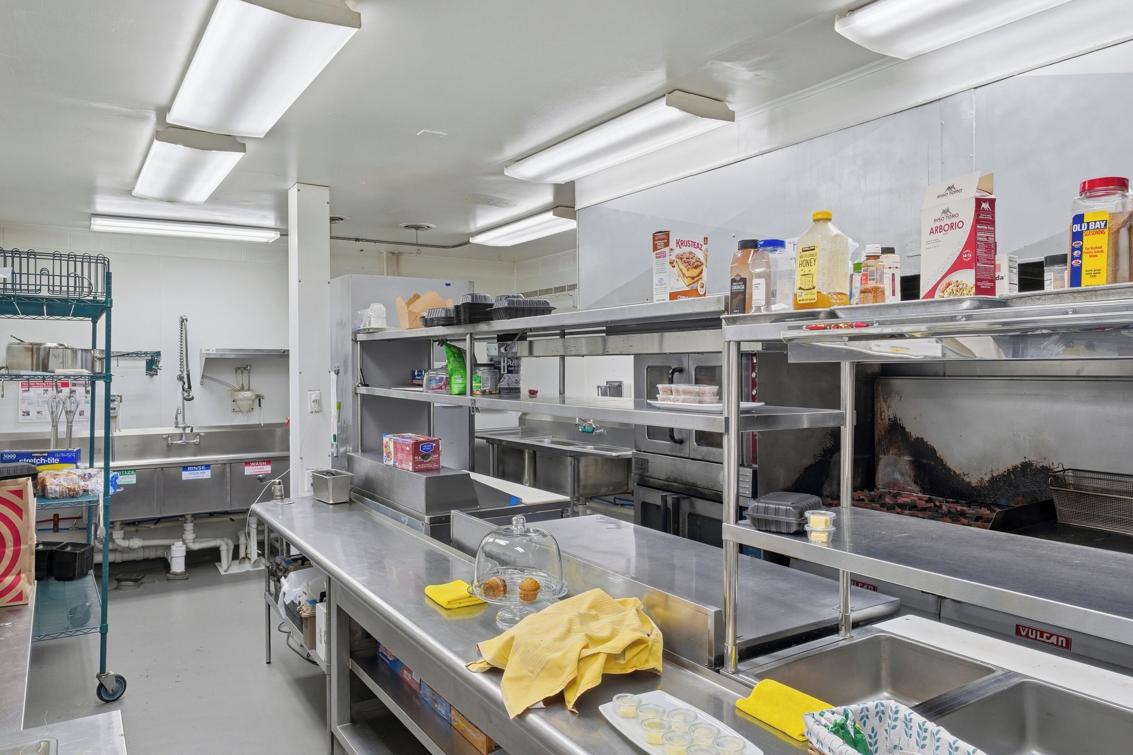 A commercial kitchen with stainless steel surfaces, various food containers, and kitchen equipment.
