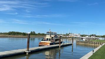Un port de plaisance avec des bateaux amarrés, une jetée en bois et un ciel bleu azur.