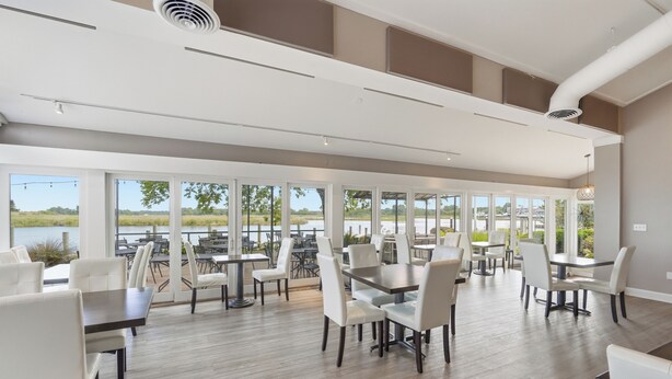 A spacious indoor dining area with large windows, tables, and chairs. - The Tilghman Island Inn (Tilghman)