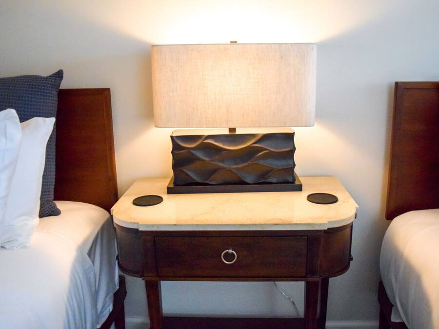 Een hotelkamer met twee bedden, een nachtkastje met een lamp en een klein lade.