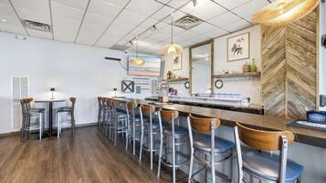 Un área de bar moderna con una barra larga, varios taburetes y un espejo grande.