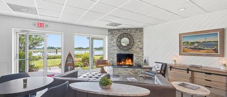 A modern lounge area with a fireplace, seating, and a view of the outdoors.