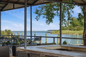 Un espace extérieur aménagé avec des tables et des chaises, offrant une vue sur un plan d’eau et la verdure environnante.
