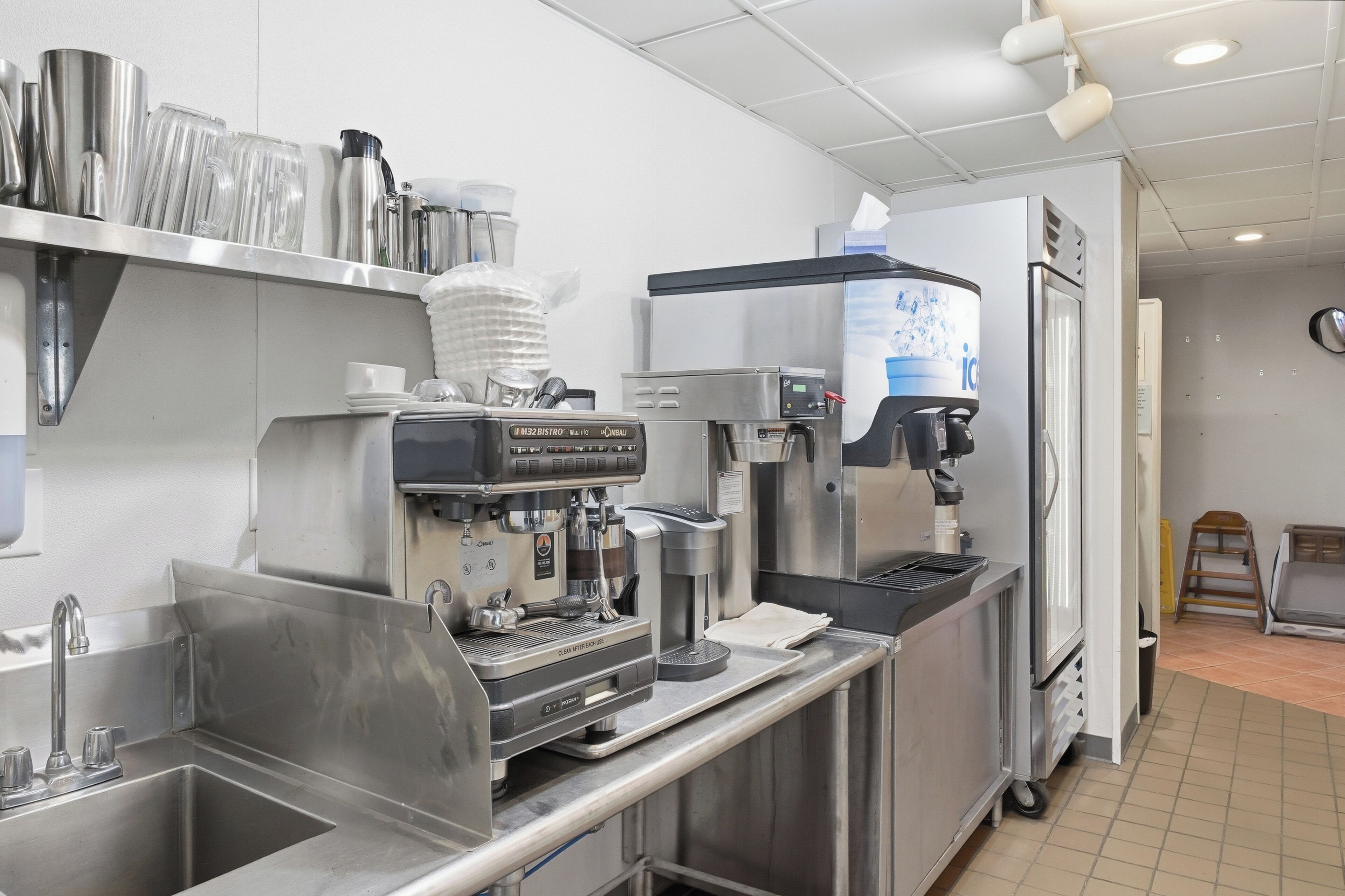 A commercial kitchen with stainless steel appliances, a coffee machine, and a water dispenser.