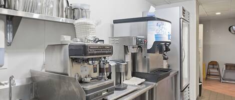 A commercial kitchen with stainless steel appliances, a coffee machine, and a water dispenser.
