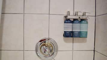 Kylpyhuoneessa on krominen suihkupää ja hyllyllä kolme pulloa kuohkeutta antavaa shampoota ja hoitoainetta.
