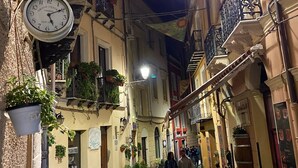 A narrow cobblestone street with buildings on either side, outdoor seating, and hanging plants. - Casa Vacanze Iglesias in Centro (Iglesias)