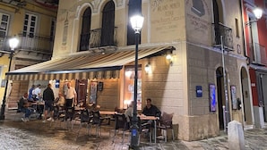 A building with multiple signs advertising various businesses, including a cafe and a restaurant. - Casa Vacanze Iglesias in Centro (Iglesias)