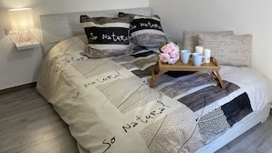 A neatly made bed with a patchwork quilt, a bedside table with a lamp, and a tray with candles and flowers. - Casa Vacanze Iglesias in Centro (Iglesias)