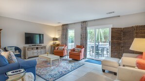 Un salon comprenant un téléviseur, deux canapés, une table basse et un tapis à motifs.