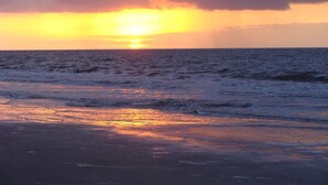 Un coucher de soleil sur l’océan, avec des vagues qui se brisent sur le rivage.
