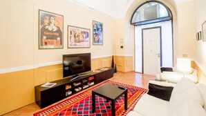 Ein Wohnzimmer mit Fernseher, Sofa und einem gemusterten Teppich.