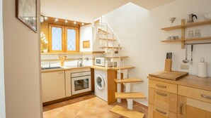 Eine kleine Küche mit Waschmaschine, Mikrowelle und einer Holztreppe.