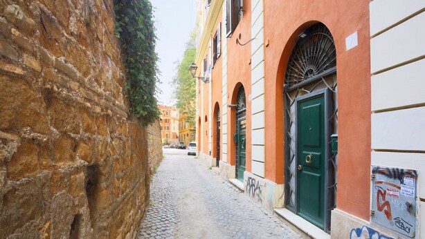 Eine enge Kopfsteinpflasterstraße, gesäumt von Gebäuden mit Rundbogenfenstern und einer grünen Tür.