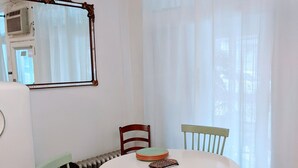 A dining area with a round table, two chairs, a radiator, and a mirror on the wall.