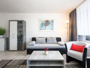 Una sala de estar moderna con un sofá, una mesa de centro, una silla, un aparador y un cuadro en la pared.