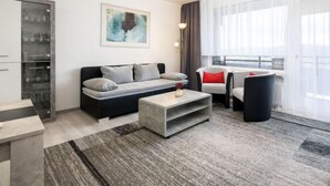 Un salon moderne comprenant un canapé, une table basse et un coin repas avec des chaises.