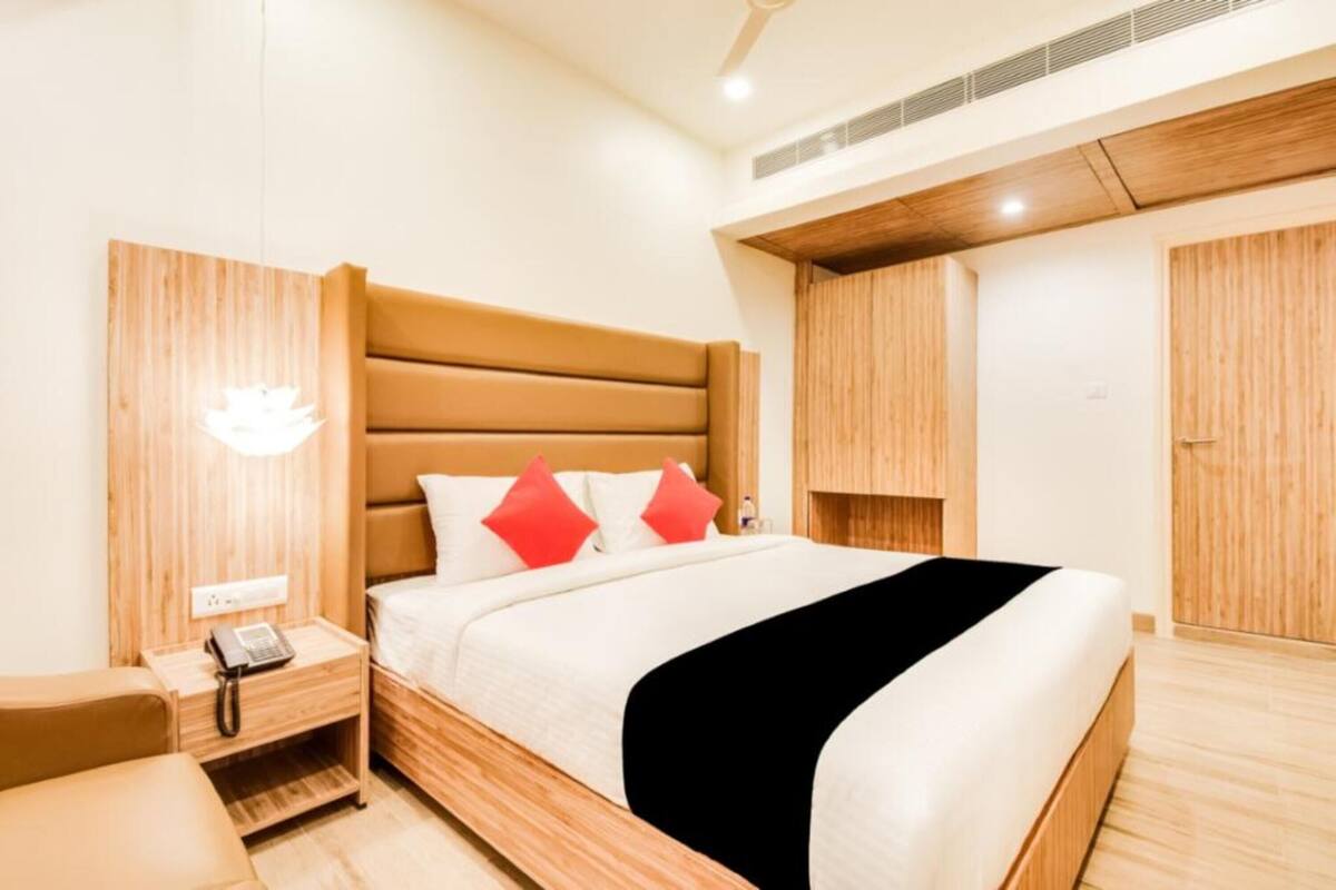 A modern hotel room with a large bed, wooden headboard, and built-in wardrobe.