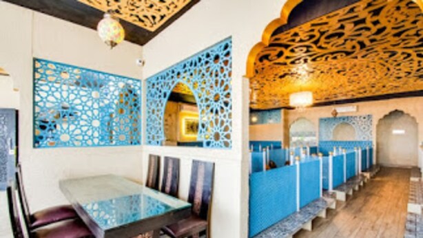 A restaurant with a long counter, blue decorative panels, and a patterned ceiling. - Inn The Centre (Nellore)