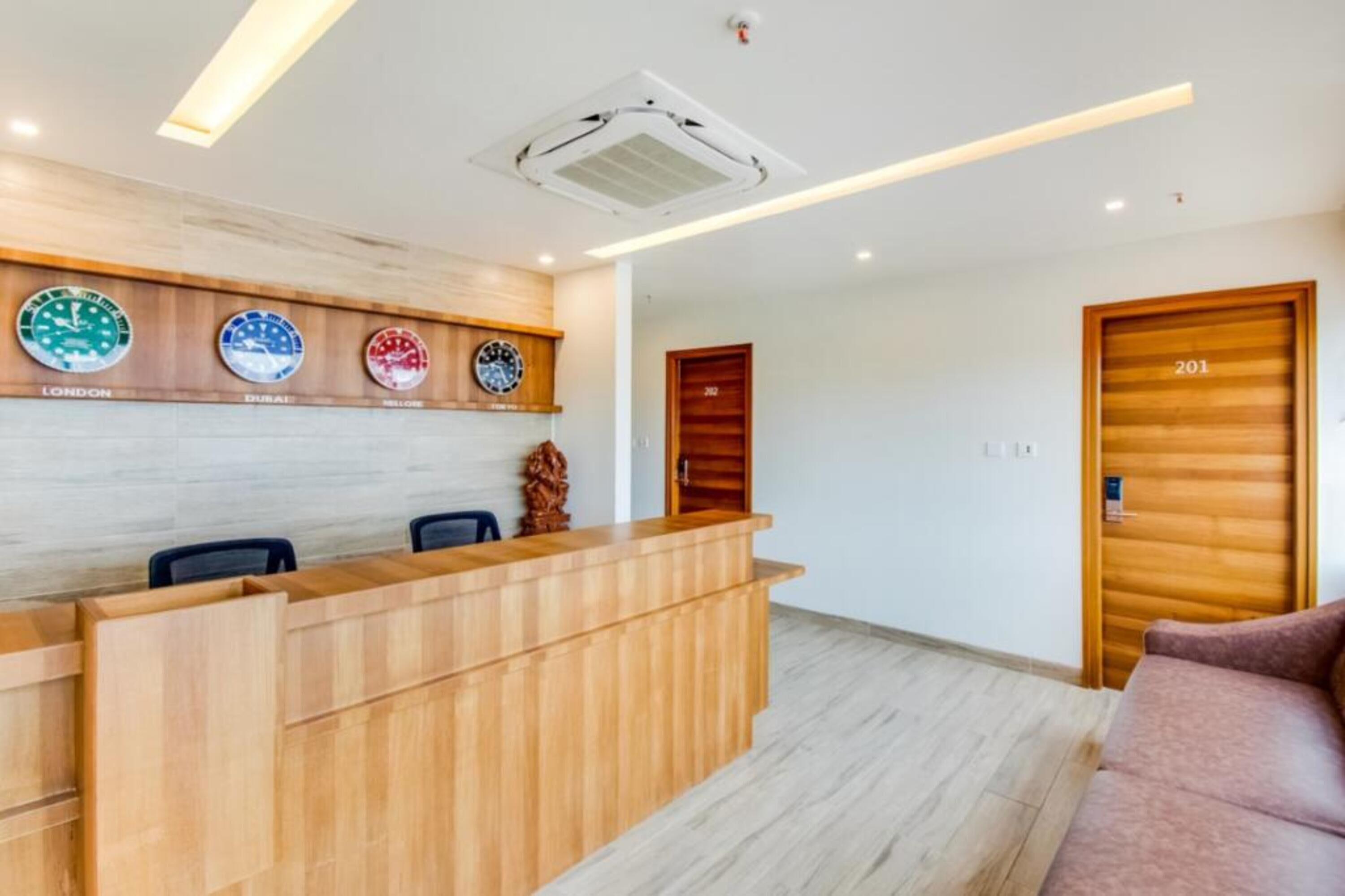Un espace d’accueil avec un comptoir en bois, une horloge et une porte portant l’inscription « 201 ».