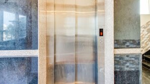 An elevator with a digital display, surrounded by stone and marble walls. - Inn The Centre (Nellore)