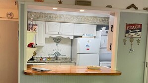 A kitchen with white cabinets, a wooden countertop, and two stools. - E13 Build family memories,  comfortable, clean (St. Simons Island)