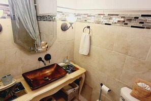 A bathroom with a large, rustic-style sink, a towel rack, a toilet, and a shower curtain.