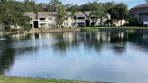 A residential area with a large pond, houses with balconies, and a grassy foreground. - E13 Build family memories,  comfortable, clean (St. Simons Island)
