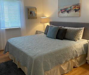 A neatly made bed with a patterned bedspread, a bedside lamp, and a framed picture on the wall.