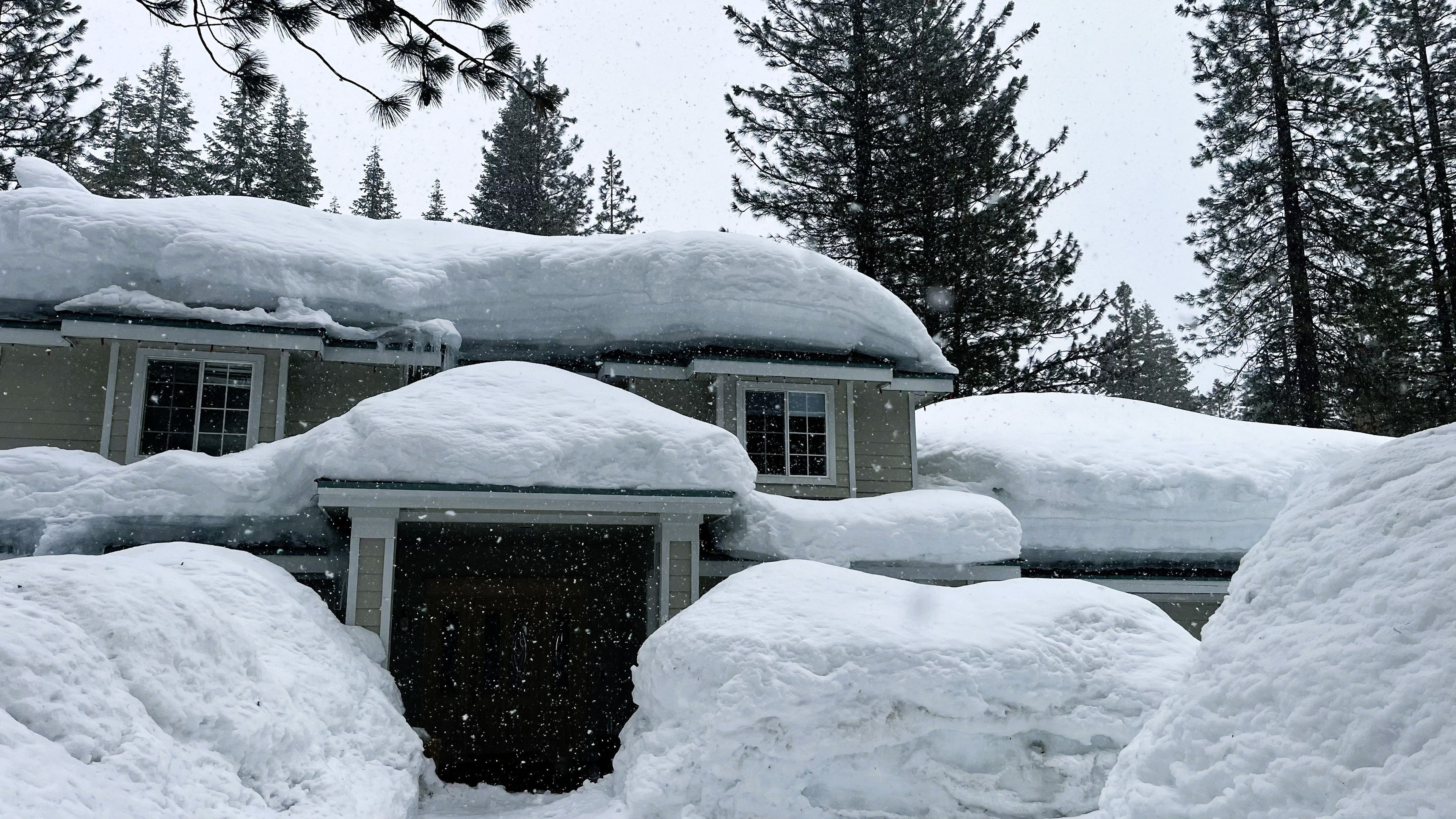 A house covered in snow with a garage entrance.