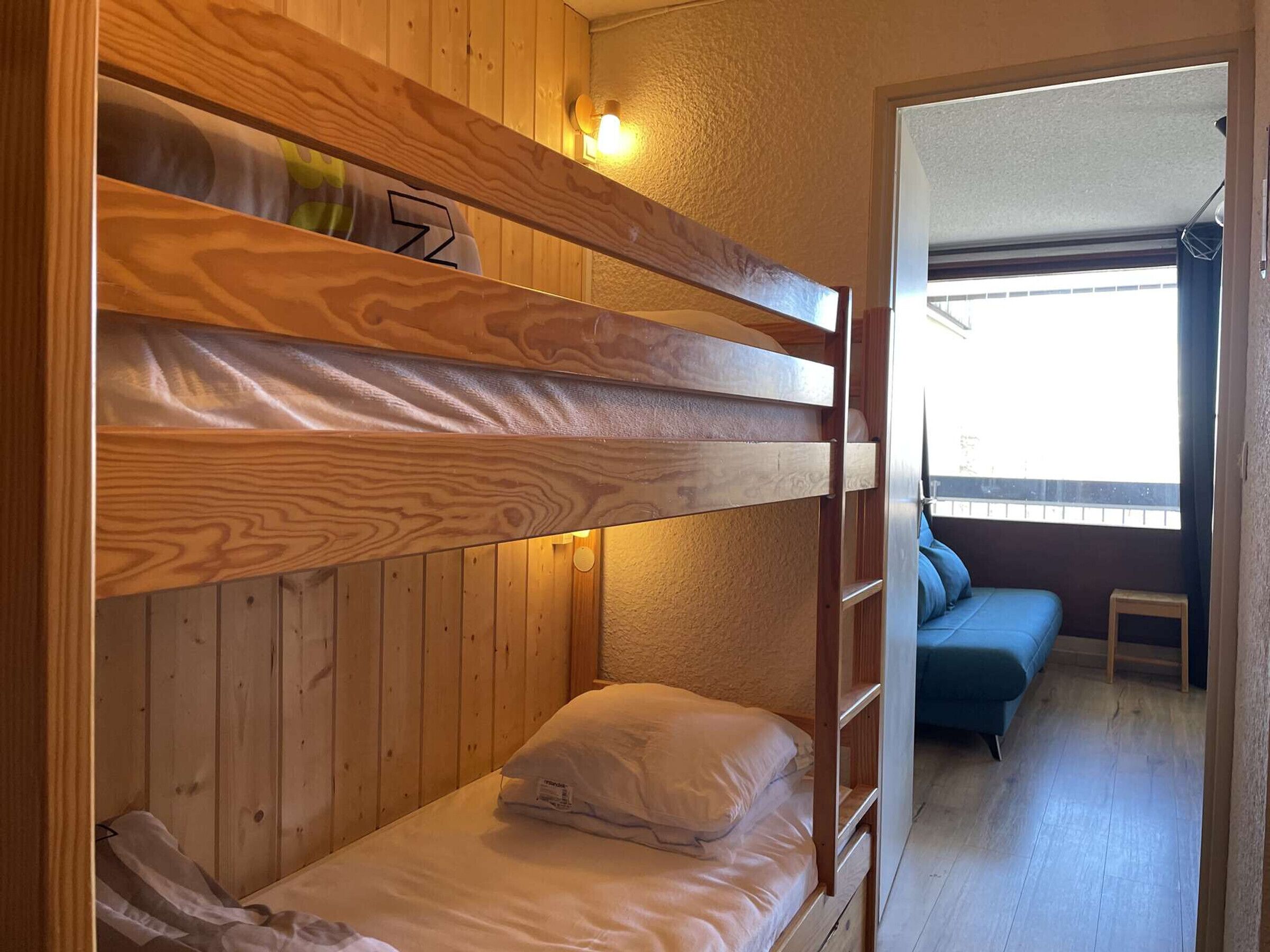 A bunk bed room with wooden walls and a window.