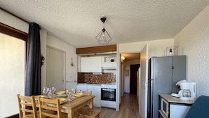 A compact living space with a dining area, kitchenette, and a seating area with a sofa.